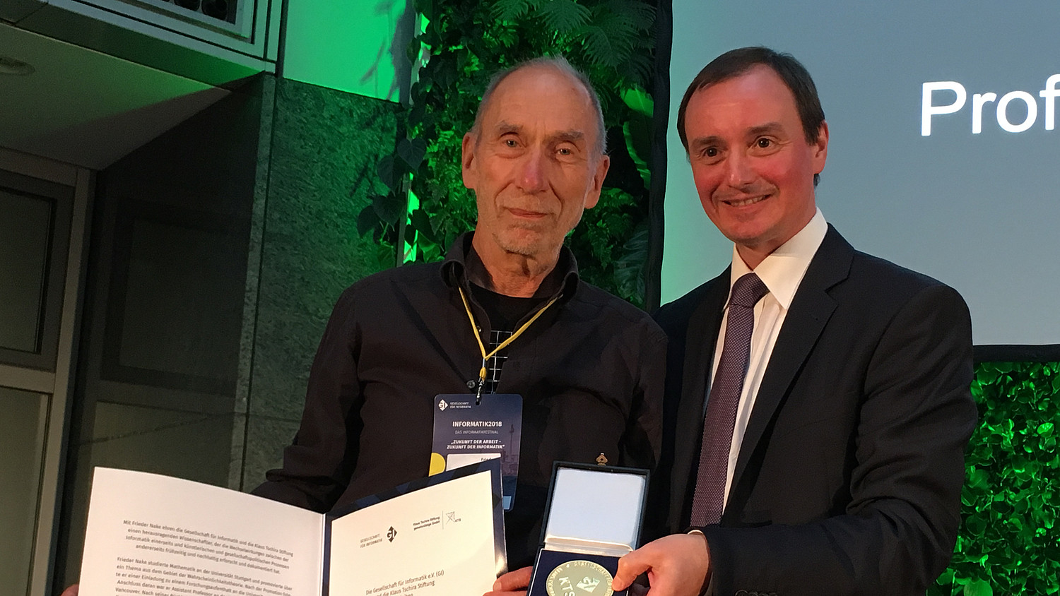 Frieder Nake und der ehemlige GI-Präsident Hannes Federrath. Nake hält seine Urkunde in die Kamera, Federrath präsentiert die Medaille