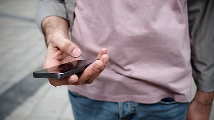 Eine Hand, die ein Handy hält und etwas eintippt