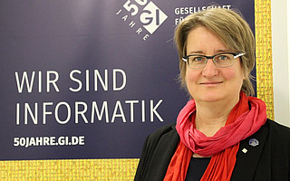 Portraitfoto von Prof. Dr. Daniela Nicklas vor GI-Hintergrund mit Text "Wir sind Informatik"