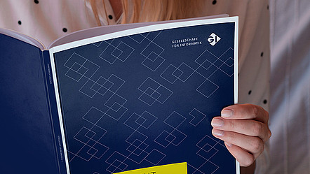 Eine Person liest im aufgeschlagenen GI-Jahresbericht 2022/23