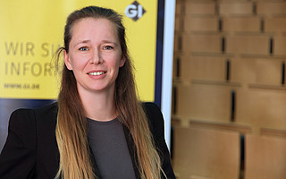 Portraitfoto von Prof. Dr. Ulrike Lucke vor GI-Hintergrund mit Text "Wir sind Informatik"