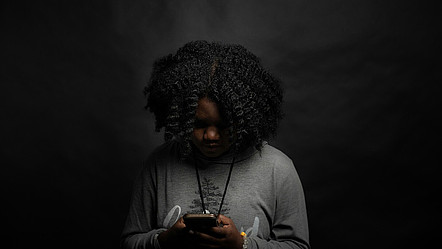 Frau im grauen Langarmshirt schaut auf ihr Smartphone.